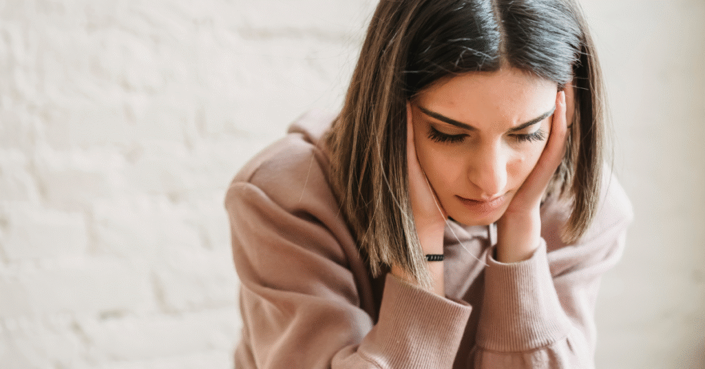 doubtful looking woman with furrowed brow holding her head in her hand